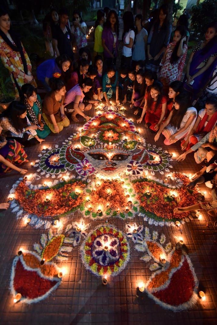 Indian girls light earthen lamps on a rangoli as they celebrate Diwali, the Festival of Lights.jpeg